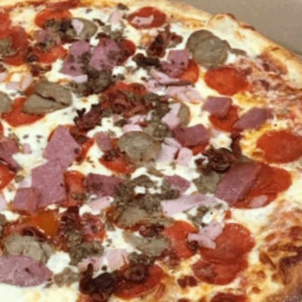 Close-up of a Master's Pizza Pasta & Grill pizza loaded with pepperoni, ham, sausage, and bacon.