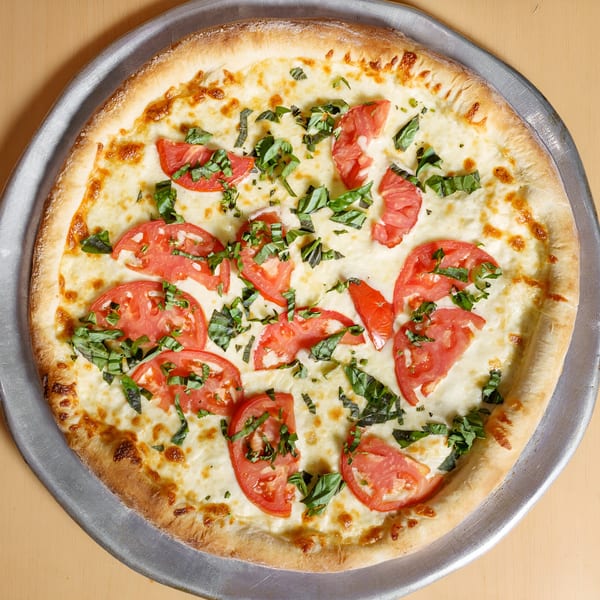 Master's Pizza Pasta & Grill's white pizza with fresh tomatoes and basil on a metal tray.